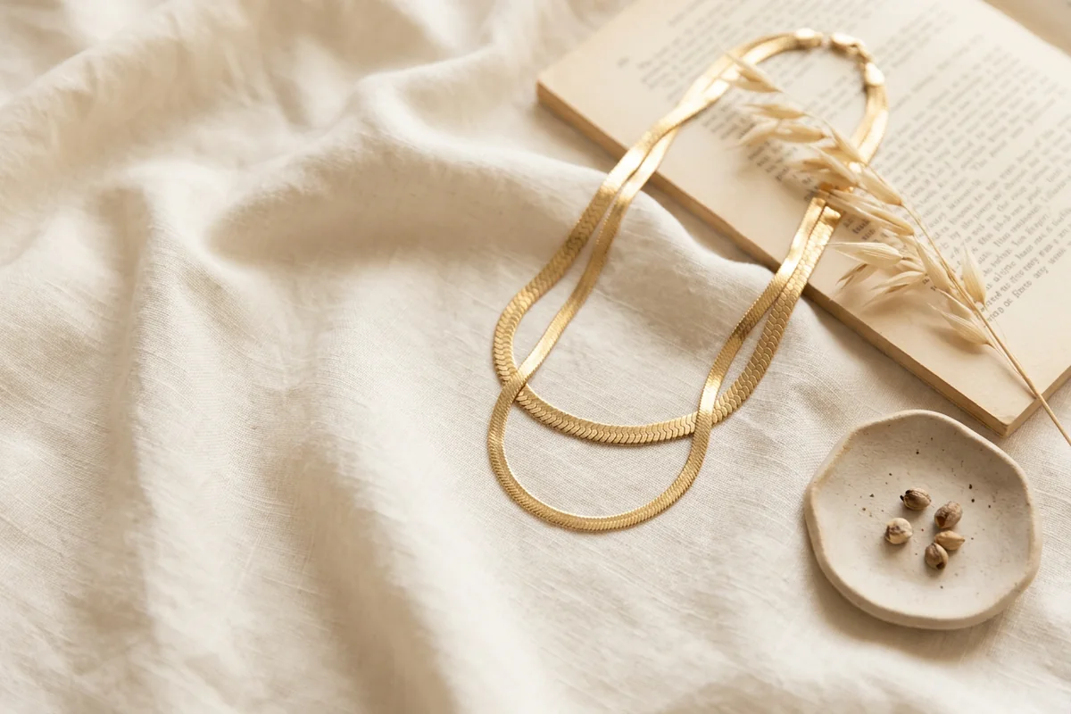 Layered waterproof gold-tone chain necklaces on a neutral linen background